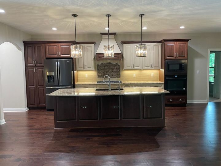Two-tone kitchen with mosaic tile backsplash arch over the range, granite island and dark hardwood floor in Plainfield, IN