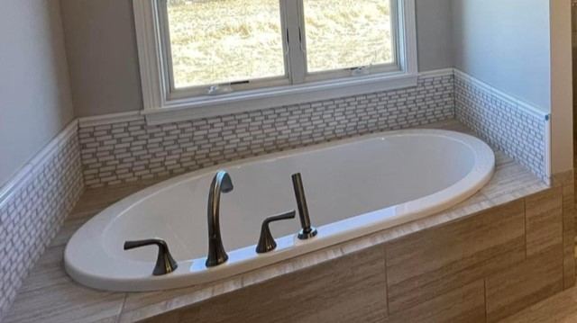 Drop-in tub with linear glass mosaic surround and stone-look tile deck in Pittsboro, IN