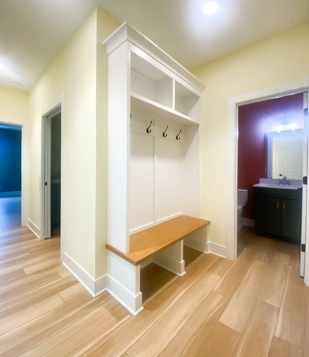 Wood-look plank tile flooring in a mudroom hall with built-in bench and coat hooks in Avon, IN