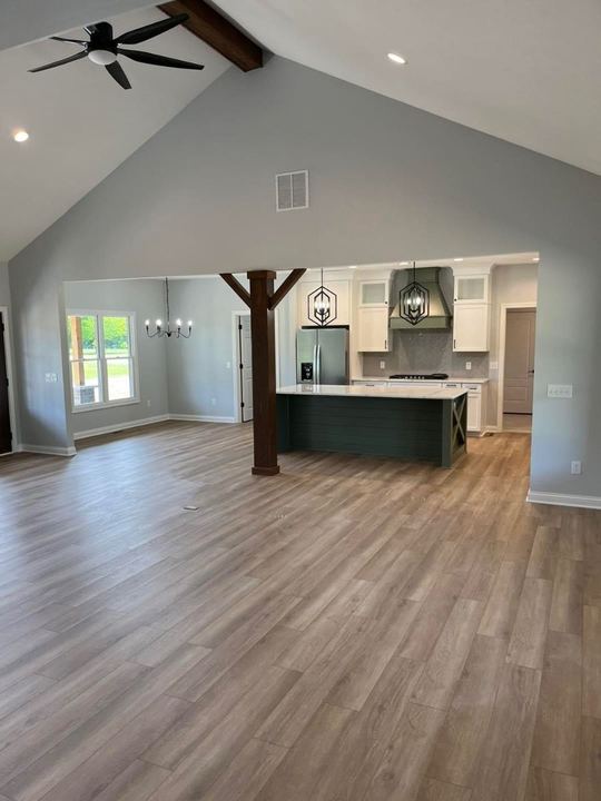 Light oak-look luxury vinyl plank across a vaulted open-concept great room and kitchen with green shiplap island in Avon, IN