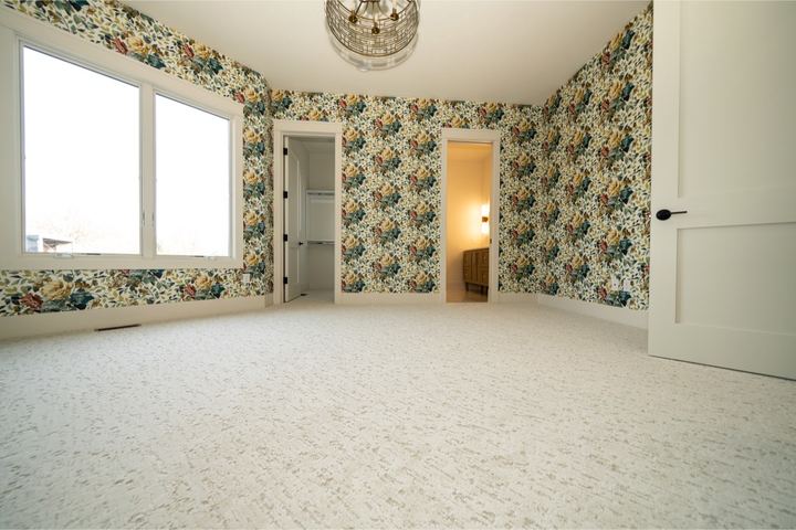 Cream patterned carpet in a bedroom with bold floral wallpaper and brass light fixture in Brownsburg, IN