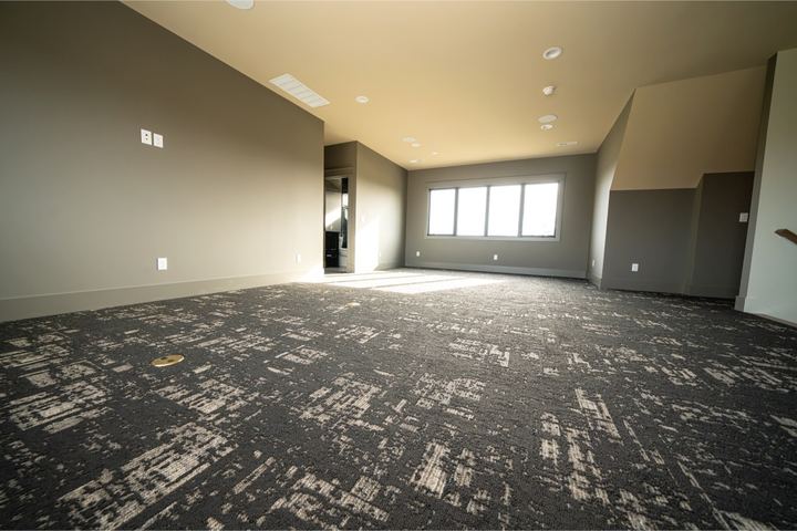Bonus room with charcoal and cream abstract patterned carpet and large sunny window in Noblesville, IN