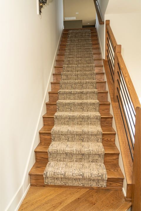Textured patterned carpet runner on oak hardwood stairs with wood and iron railing in Plainfield, IN
