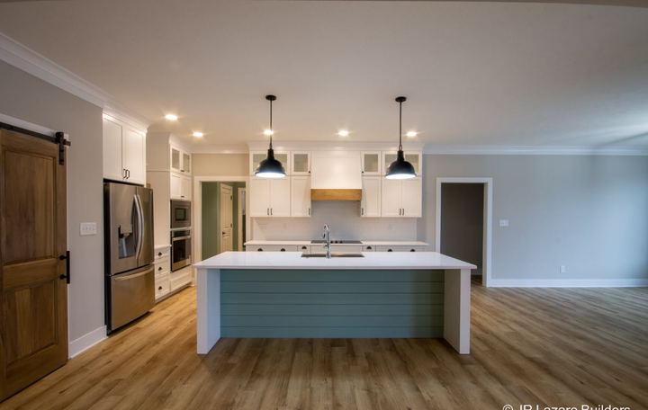 Light luxury vinyl plank flooring in an open kitchen with teal shiplap island and picket tile backsplash in Avon, IN