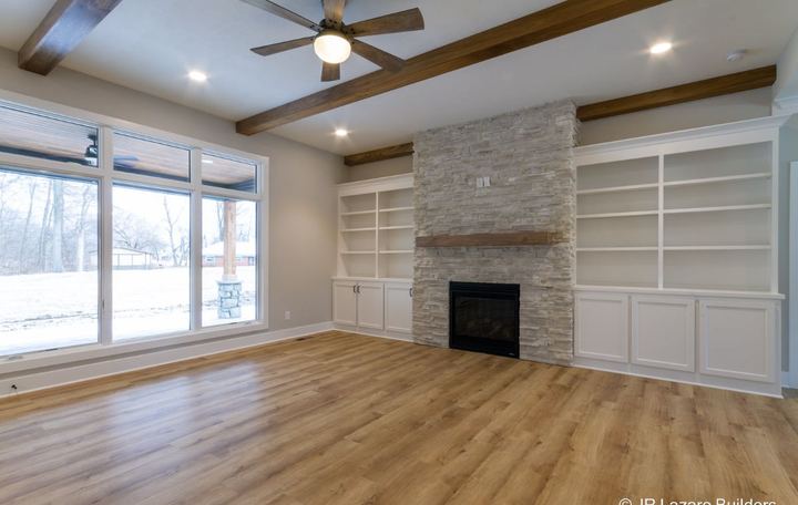 Light oak-look plank flooring in a living room with stacked stone fireplace and built-in shelving in Avon, IN
