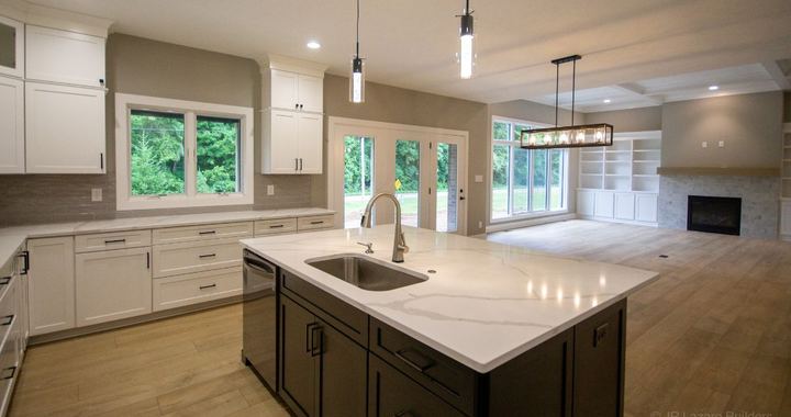 Open kitchen with marbled quartz island, taupe subway backsplash and wood-look flooring into the living room in Avon, IN