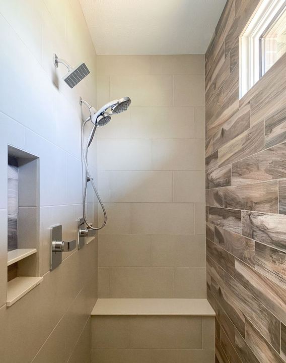 Master shower with beige large-format tile, wood-look accent wall, bench seat and double niche in Avon, IN
