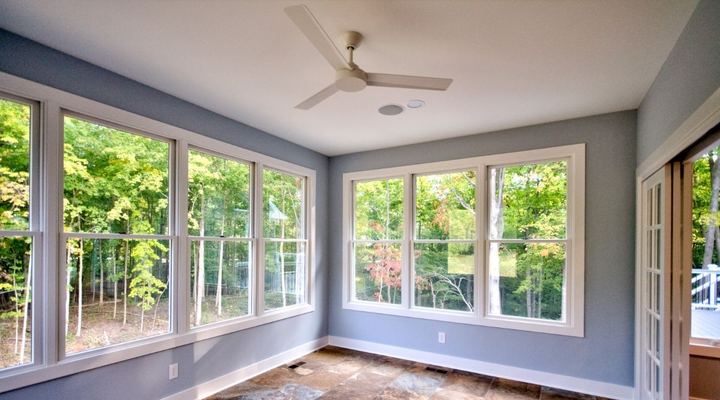 Sunroom with rust and gray slate-look tile floor, blue walls and wooded window views in Avon, IN