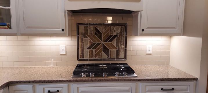 Cream subway tile backsplash with wood-look mosaic star medallion above the cooktop in Avon, IN