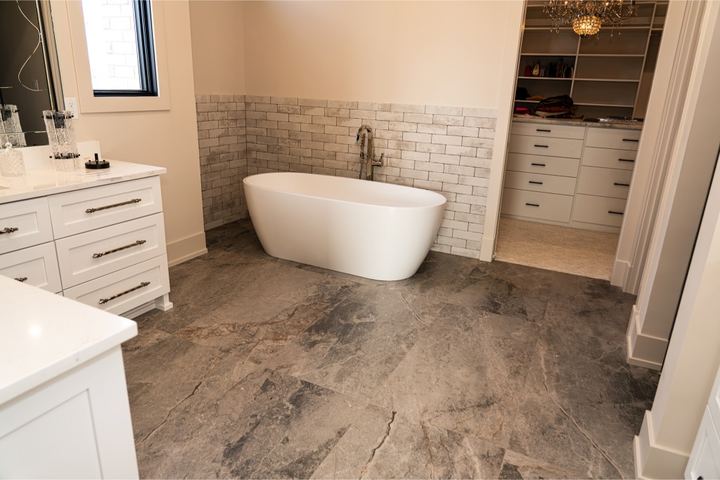Master bathroom with gray stone-look tile floor, brick-pattern tile wainscot and freestanding soaker tub in Brownsburg, IN