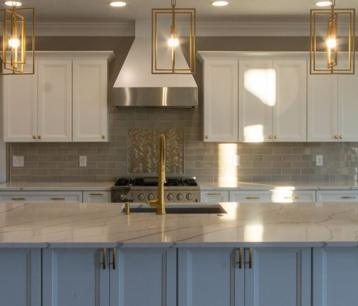 Kitchen with taupe subway tile backsplash, herringbone accent over the range and brushed gold faucet in Avon, IN
