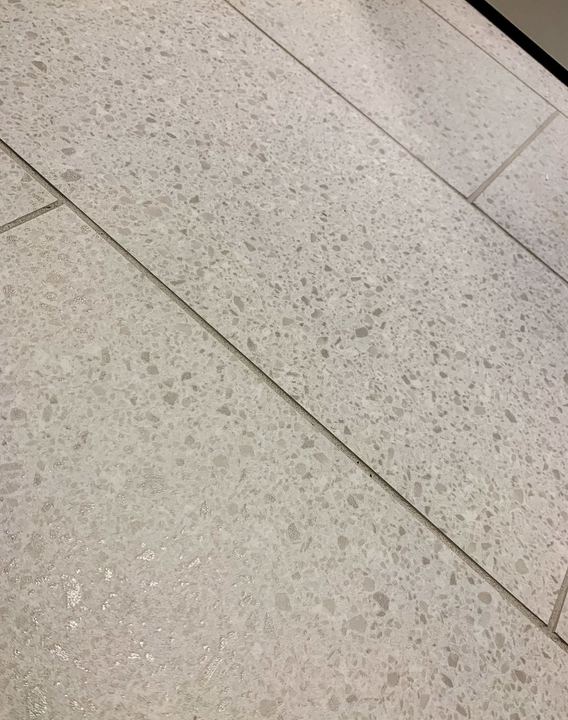 Close-up of terrazzo-look porcelain floor tile in soft gray with speckled aggregate pattern in Avon, IN