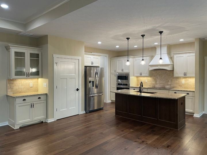 Kitchen with tumbled travertine backsplash, cream cabinets and dark hickory hardwood floors in Plainfield, IN