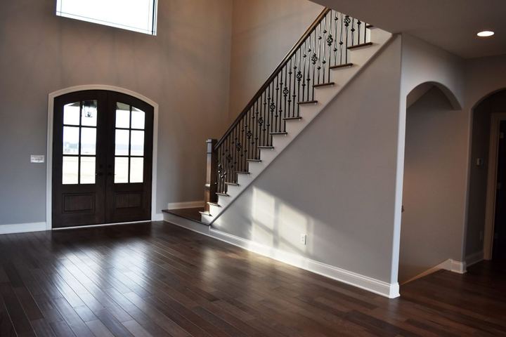 Two-story foyer with dark hardwood flooring, arched double front doors and iron-spindle staircase in Plainfield, IN