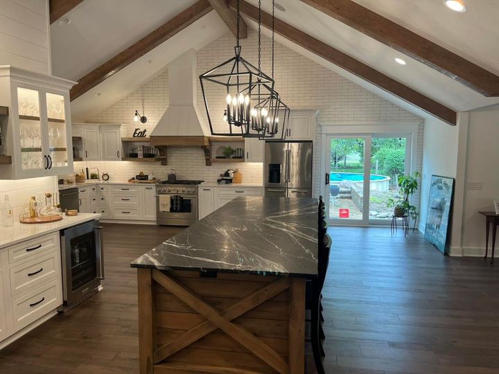 Farmhouse kitchen with white brick tile run up the vaulted gable wall, wood beams and black soapstone island in Pittsboro, IN