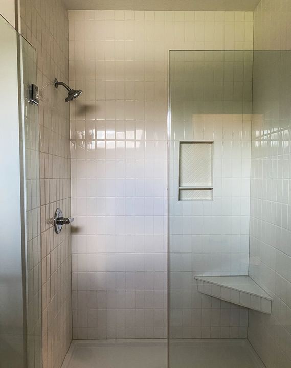 Walk-in shower with white vertical-stacked tile, herringbone niche and corner bench in Avon, IN