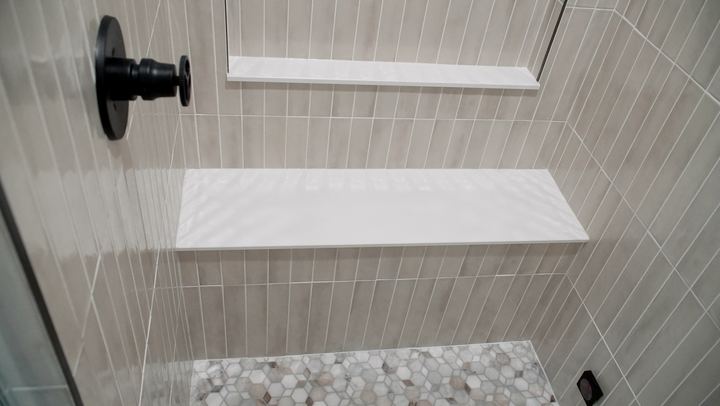 Steam shower with vertical-stacked tile, floating shelves and hex marble mosaic floor in Westfield, IN