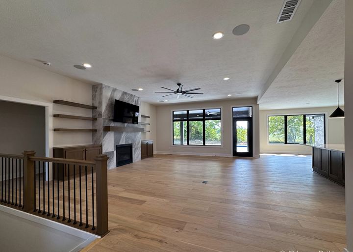 Wide-plank white oak hardwood in an open great room with marble-look tile fireplace in Danville, IN