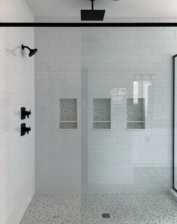 Walk-in shower with white subway tile, three mosaic-lined niches, penny tile floor and matte black fixtures in Avon, IN