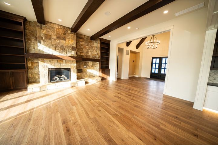 Wide-plank white oak hardwood in a great room with stone fireplace and wood ceiling beams in Avon, IN