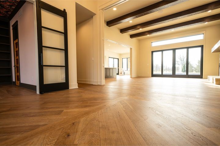 Open great room with wide plank oak hardwood flooring, dark ceiling beams and wall of windows in Danville, IN