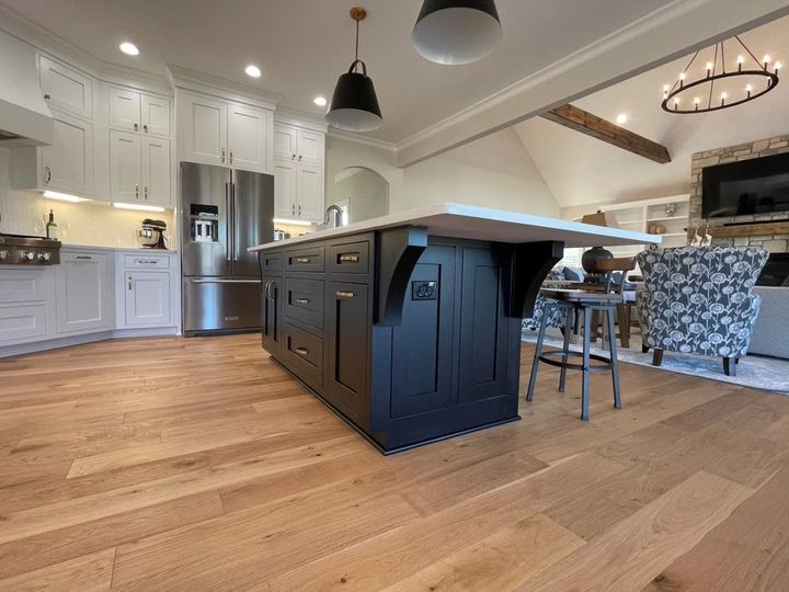 Wide-plank white oak hardwood flooring in an open kitchen with navy island and white cabinets in Avon, IN