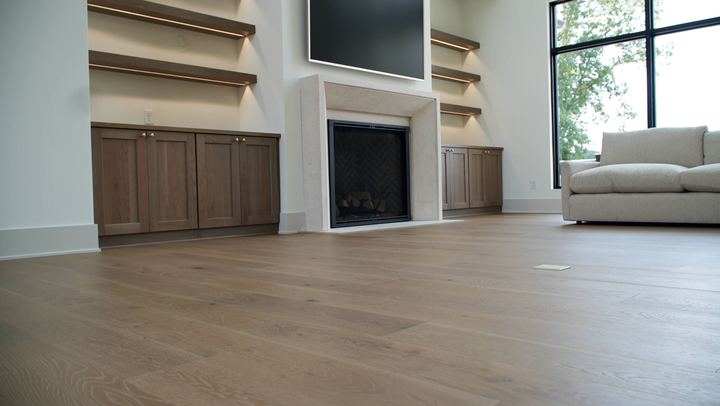 Wide-plank white oak engineered hardwood in a modern living room with stone fireplace and built-ins in Avon, IN