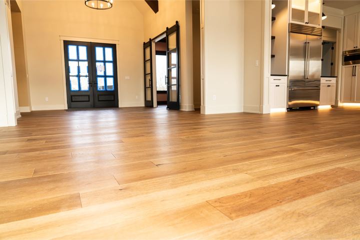Wide-plank white oak hardwood flooring in an open great room with black French doors and vaulted ceiling in Avon, IN