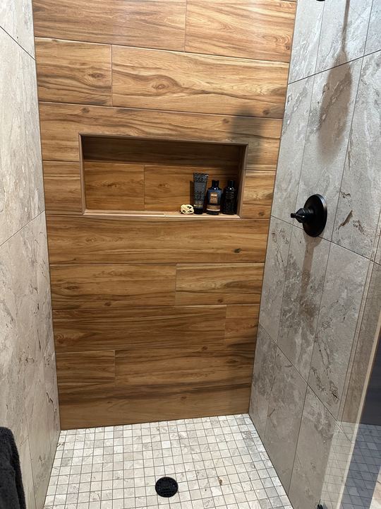 Walk-in tile shower with wood-look plank accent wall, stone-look walls, mosaic floor and black fixtures in Avon, IN